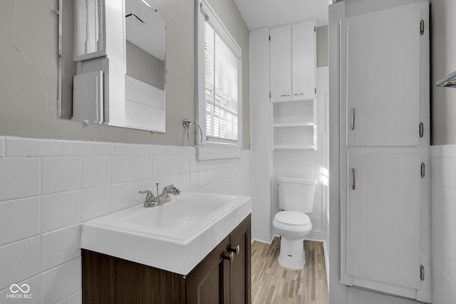 bathroom with toilet, hardwood / wood-style flooring, vanity, and tile walls