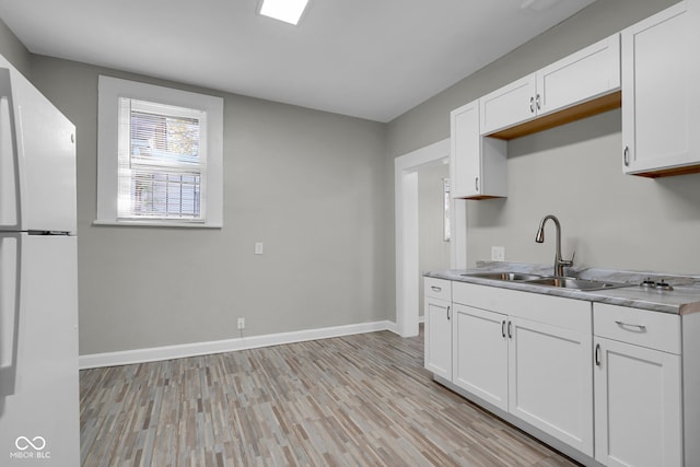 kitchen with white cabinets, white fridge, sink, and light wood-type flooring