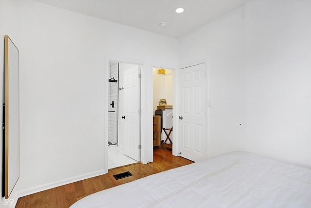 bedroom with connected bathroom and light wood-type flooring