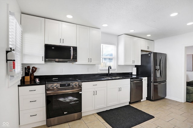 kitchen with white cabinetry, stainless steel appliances, sink, and a textured ceiling