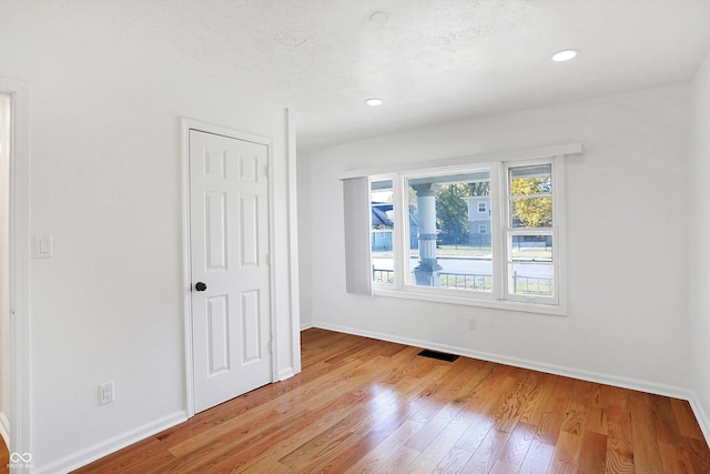 unfurnished room featuring light hardwood / wood-style flooring and a textured ceiling