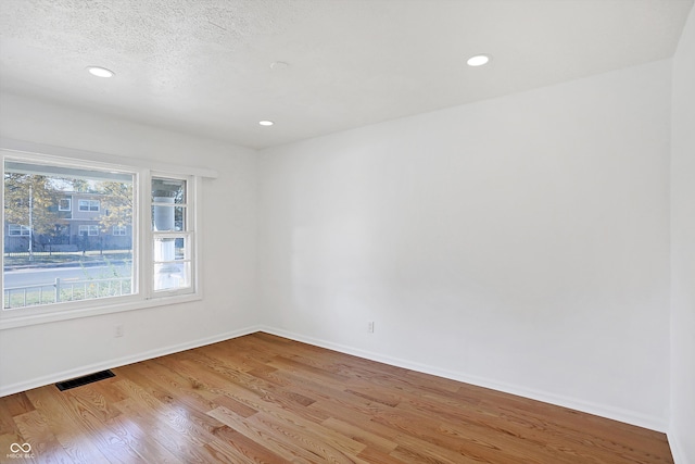 unfurnished room featuring a textured ceiling and light wood-type flooring