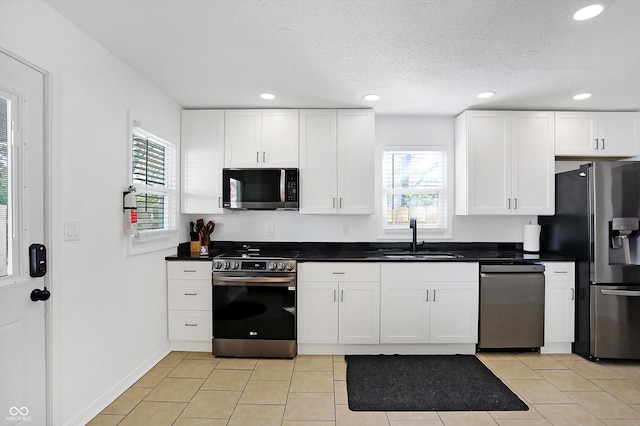 kitchen with a wealth of natural light, sink, appliances with stainless steel finishes, and white cabinets