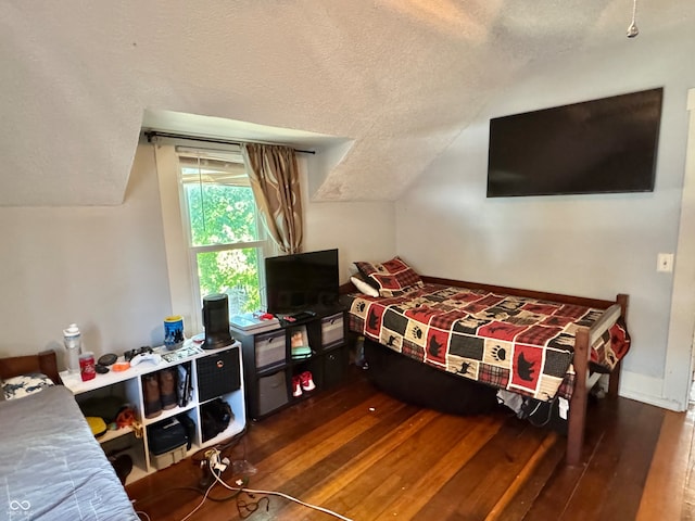 bedroom with dark hardwood / wood-style floors, a textured ceiling, and vaulted ceiling