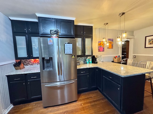 kitchen featuring a breakfast bar area, dark wood-type flooring, stainless steel refrigerator with ice dispenser, kitchen peninsula, and pendant lighting