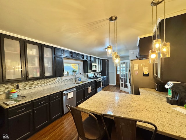 kitchen featuring appliances with stainless steel finishes, a healthy amount of sunlight, decorative light fixtures, and dark hardwood / wood-style flooring