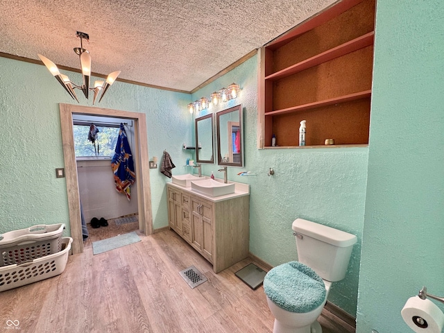 bathroom featuring toilet, hardwood / wood-style floors, a notable chandelier, vanity, and a textured ceiling