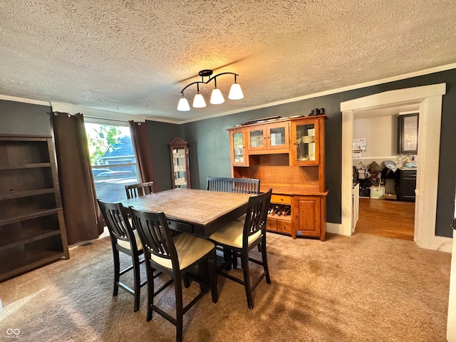 dining area with ornamental molding, a textured ceiling, and carpet floors