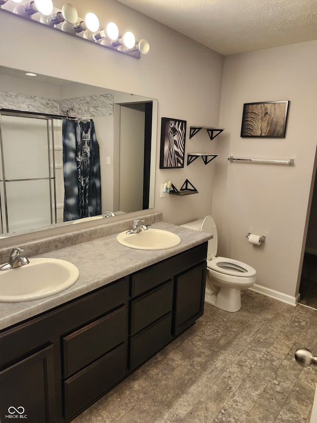 bathroom with vanity, toilet, walk in shower, and a textured ceiling