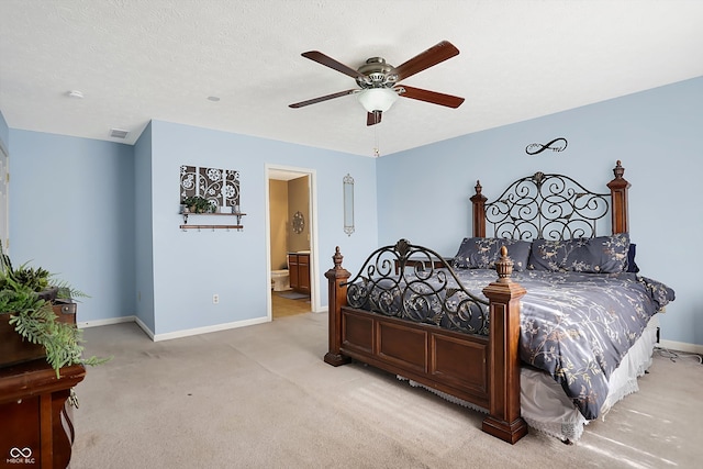 bedroom with ceiling fan, ensuite bath, light colored carpet, and a textured ceiling