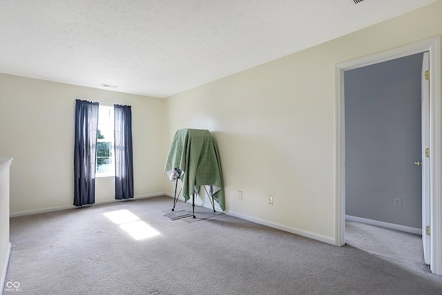 empty room with light carpet and a textured ceiling