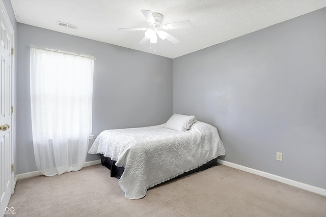 bedroom with light carpet, ceiling fan, and a textured ceiling