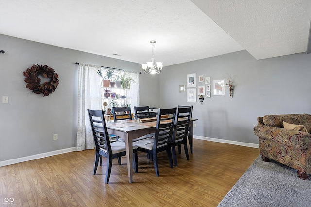 dining room with a notable chandelier, hardwood / wood-style flooring, and a textured ceiling