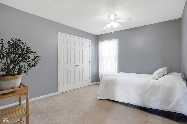 carpeted bedroom with ceiling fan, a closet, and a textured ceiling