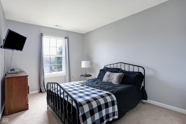 bedroom featuring light colored carpet and a textured ceiling