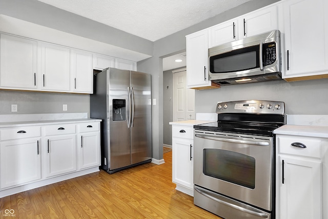 kitchen featuring stainless steel appliances, white cabinetry, a textured ceiling, and light hardwood / wood-style flooring