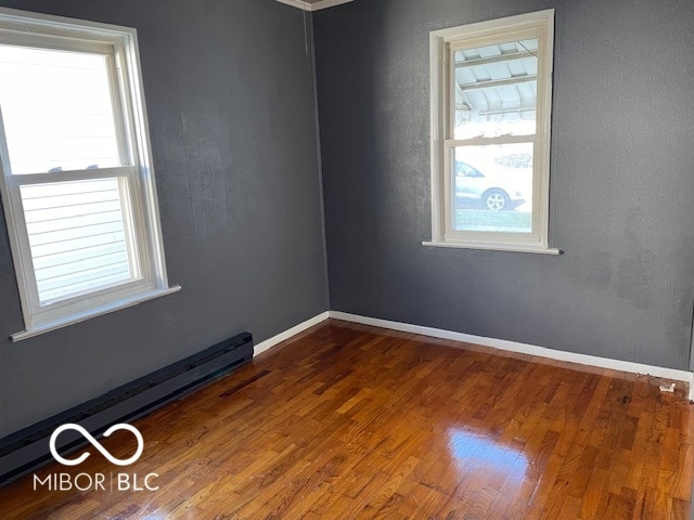 empty room with dark wood-type flooring and baseboard heating