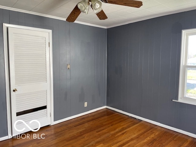 unfurnished room with wood walls, ceiling fan, dark hardwood / wood-style floors, and crown molding