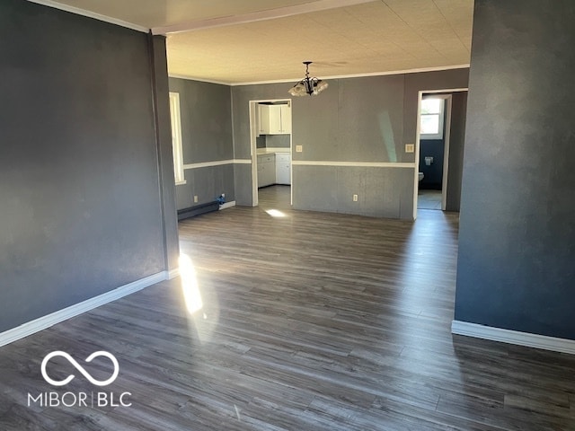 unfurnished room with crown molding, a baseboard heating unit, dark hardwood / wood-style flooring, and a notable chandelier