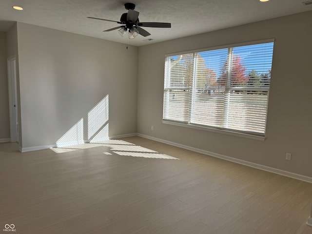 empty room featuring a textured ceiling, light hardwood / wood-style floors, and ceiling fan