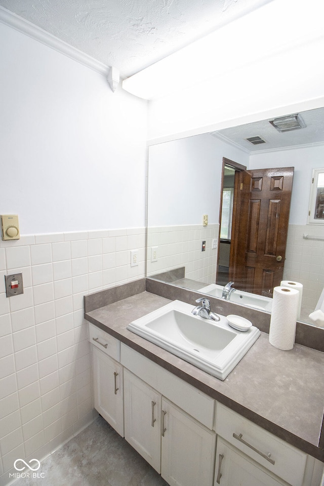 bathroom with tile walls, vanity, a textured ceiling, and ornamental molding