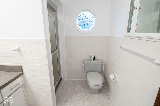 bathroom with vanity, toilet, and tile walls