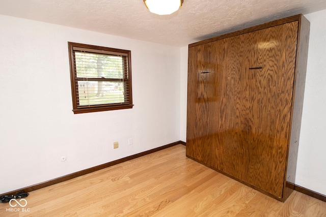 spare room featuring light hardwood / wood-style floors and a textured ceiling