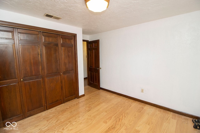 unfurnished bedroom with light hardwood / wood-style floors, a closet, and a textured ceiling