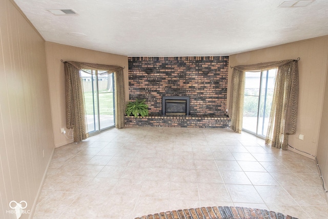 unfurnished living room with light tile patterned flooring, a textured ceiling, and a wealth of natural light