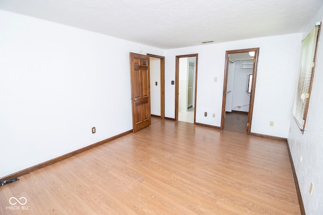 unfurnished bedroom with a closet, a walk in closet, ensuite bathroom, and light wood-type flooring