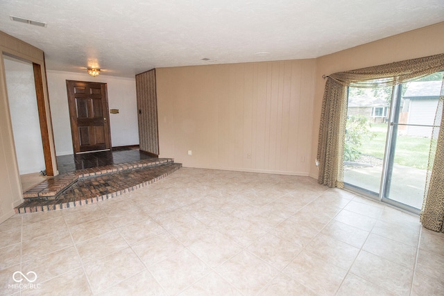 unfurnished living room featuring a textured ceiling and light tile patterned flooring