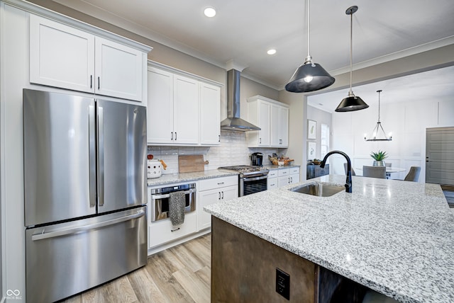 kitchen with sink, wall chimney exhaust hood, light stone counters, white cabinetry, and stainless steel appliances