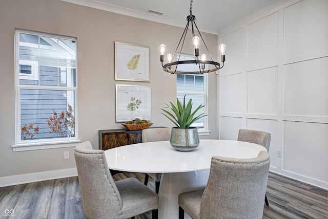 dining room with dark hardwood / wood-style floors, ornamental molding, and an inviting chandelier