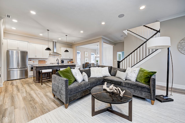 living room with sink, light hardwood / wood-style flooring, and ornamental molding