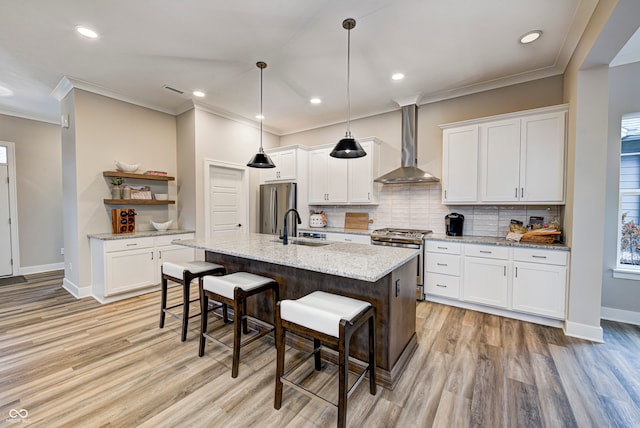 kitchen with wall chimney exhaust hood, white cabinetry, stainless steel appliances, and a kitchen island with sink