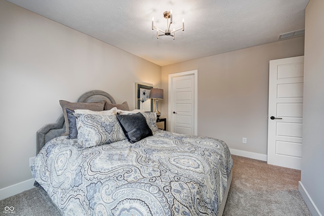 bedroom featuring light colored carpet, a textured ceiling, and a notable chandelier