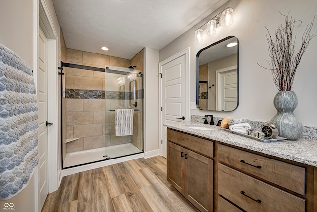 bathroom with hardwood / wood-style floors, vanity, walk in shower, and a textured ceiling