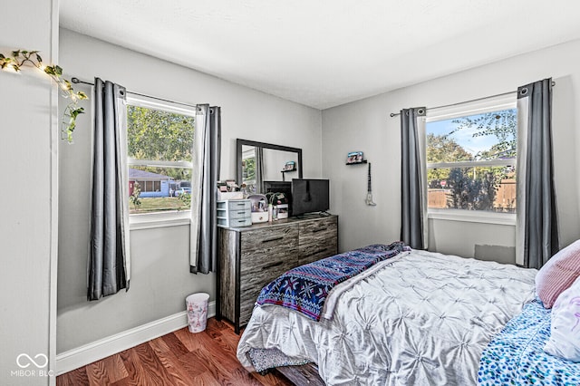 bedroom with multiple windows and dark hardwood / wood-style floors