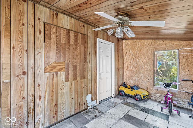 interior space featuring wood ceiling, wood walls, lofted ceiling, and ceiling fan