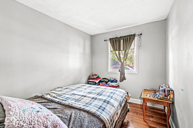 bedroom with hardwood / wood-style floors and a textured ceiling