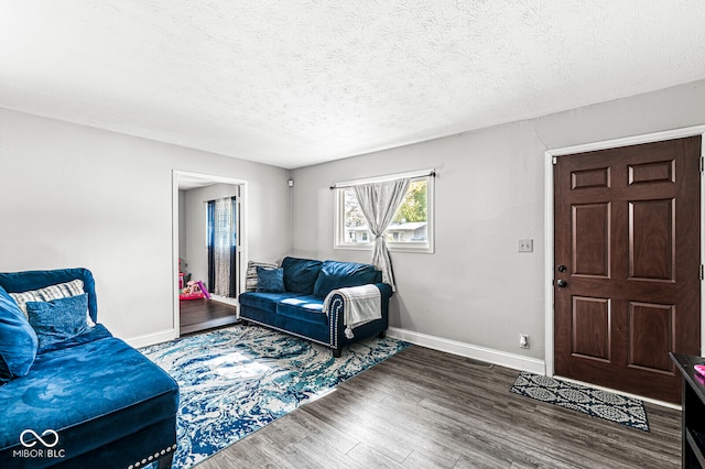 living room featuring dark wood-type flooring and a textured ceiling