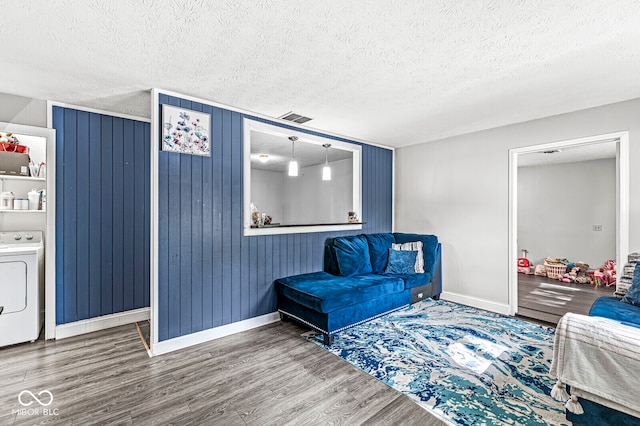 living area featuring washer / dryer, a textured ceiling, and hardwood / wood-style flooring