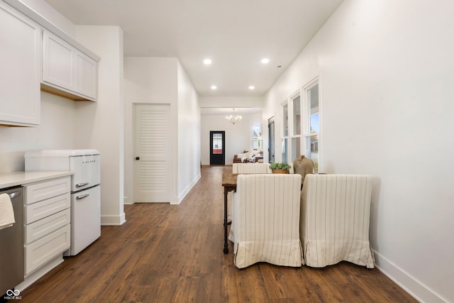 kitchen with stainless steel dishwasher, white cabinets, dark hardwood / wood-style floors, and an inviting chandelier