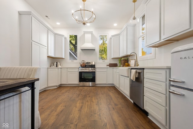 kitchen with appliances with stainless steel finishes, hanging light fixtures, custom exhaust hood, white cabinets, and dark wood-type flooring