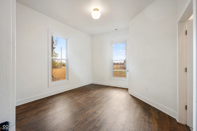 unfurnished room featuring dark wood-type flooring and plenty of natural light