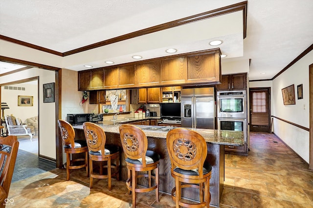 8530 Helmsman Cir, Indianapolis, IN 46256 - kitchen with stainless steel appliances, ornamental molding, stone finish floors, light stone countertops, and a peninsula