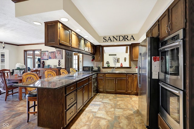 8530 Helmsman Cir, Indianapolis, IN 46256 - kitchen featuring appliances with stainless steel finishes, a kitchen bar, light stone finish floors, dark stone counters, and a textured ceiling