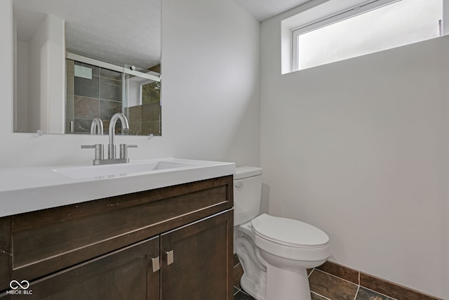 bathroom featuring vanity, toilet, a textured ceiling, and tile patterned flooring