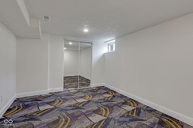 basement featuring a textured ceiling and carpet