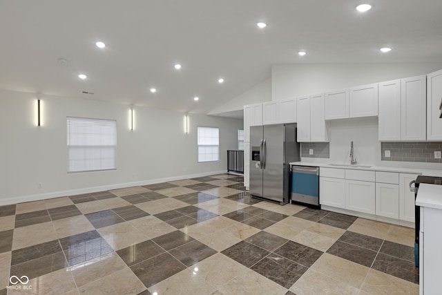 kitchen with lofted ceiling, decorative backsplash, appliances with stainless steel finishes, and white cabinets